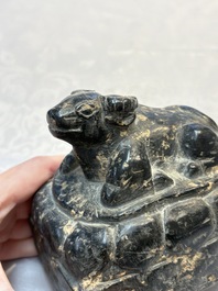 A Chinese carved black stone paper weight in the shape of a reclining buffalo on a lotus throne, Northern and Southern dynasties