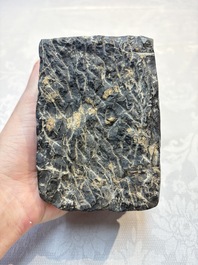 A Chinese carved black stone paper weight in the shape of a reclining buffalo on a lotus throne, Northern and Southern dynasties