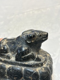 A Chinese carved black stone paper weight in the shape of a reclining buffalo on a lotus throne, Northern and Southern dynasties