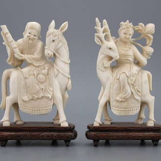 A pair of Chinese carved ivory figures on a wooden base, early 20th C.