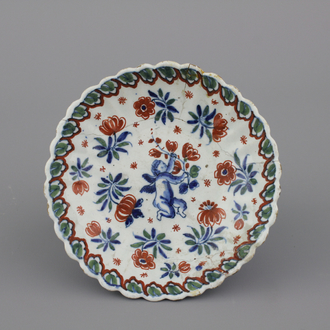 A Dutch Delft polychrome fluted saucer plate with a putto, early 18th C.