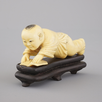 A Chinese carved ivory figure of a boy reading a book, 19/20th C.