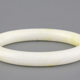 A white jadeite bangle with yellow incrustation, early 20th C.