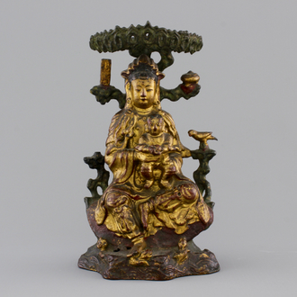 A Chinese bronze and gilt Buddha with child, seated beneath a bodhi tree, 17/18th C.