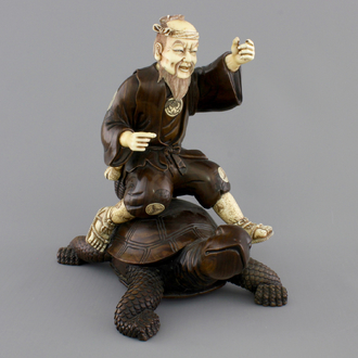 A signed Japanese carved ivory and wood figure of an immortal seated on a turtle, 19th C.