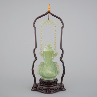 A Chinese carved green jadeite vase and cover on elaborate wooden stand, 19/20th C.