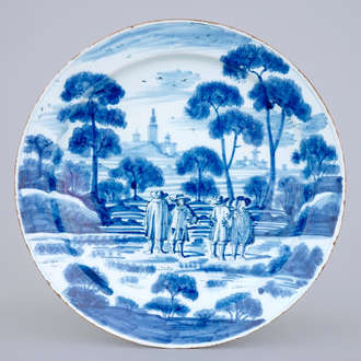 A large Dutch Delft blue and white dish with noblemen in a landscape setting, 18th C.