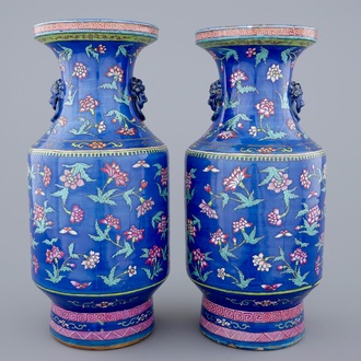 A pair of Chinese blue ground famille rose vases with flowers, 19th C.