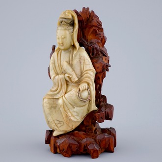 Une figure de Guanyin en pierre de savon sur socle en bois sculpté, 18/19ème