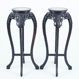 A pair of tall round Chinese carved wood stands with marble top, 19/20th C.