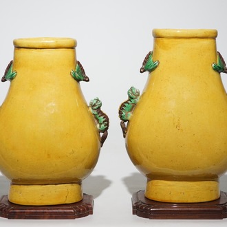 Une paire de vases de forme hu en porcelaine de Chine jaune monochrome sur socles en bois, 19/20ème