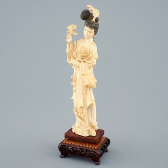 A Chinese carved ivory figure of a beauty with flowers on wooden base, early 20th C.