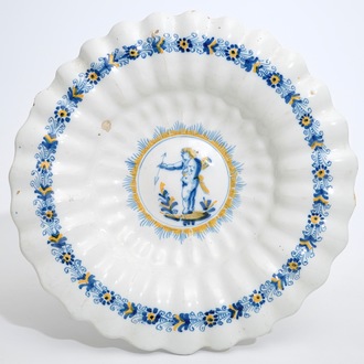 A Dutch Delftware gadrooned dish with a putto in blue and yellow, Haarlem, 17th C.