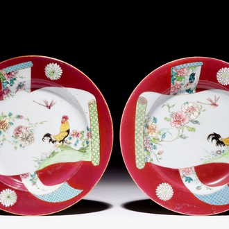 Une paire d'assiettes en porcelaine de Chine famille rose à décor de coqs sur fond rouge rubis, Yongzheng