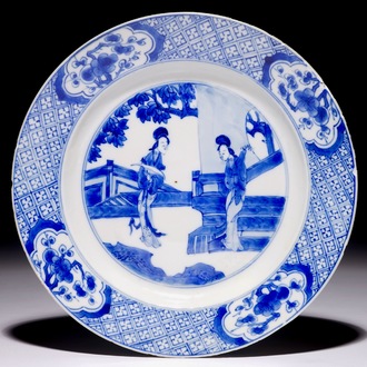 Une assiette en porcelaine de Chine bleu et blanc à décor de "dames longues" dans un jardin, Kangxi