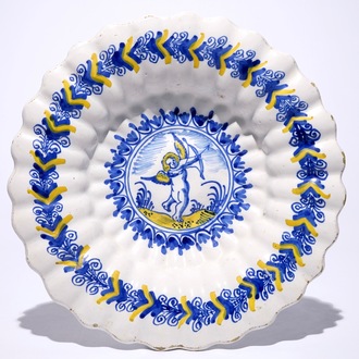 A Dutch Delftware gadrooned dish with a putto in blue and yellow, Haarlem, 17th C.