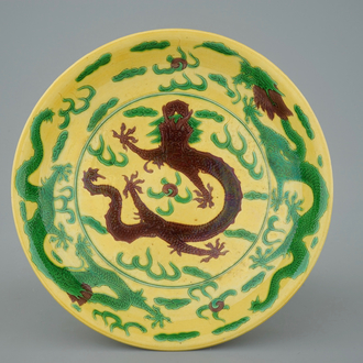 Un plat en porcelaine de Chine à décor de dragons en vert et aubergine sur fond jaune, marque de Kangxi, 19ème