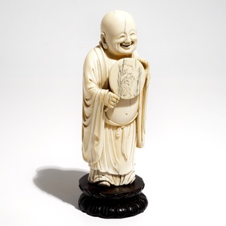 A Chinese carved ivory figure of Buddha holding a fan, on lotus-shaped base, 19th C.