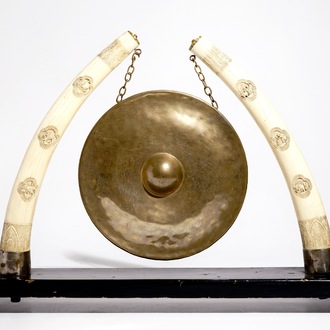 Un gong chinois en laiton orné de deux défenses en ivoire sculpté, 19/20ème