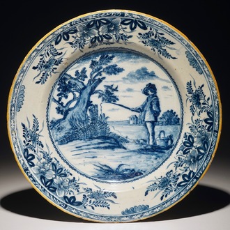 Un plat en faïence de Delft bleu et blanc figurant "Le jeune pêcheur" d'après Bloemaert, 18ème