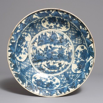 A large Chinese blue and white Swatow dish with a boat in a landscape, Ming