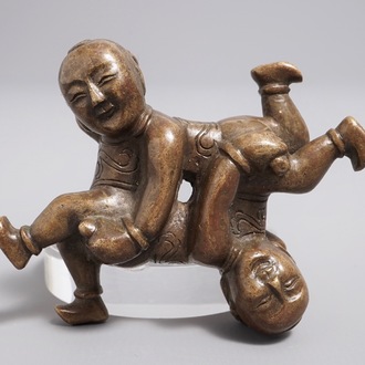 A Chinese bronze scroll or paper weight shaped as a pair of wrestling boys, 18/19th C.