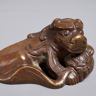 A Chinese bronze scroll or paper weight shaped as a Buddhist lion or Shishi with a ball, 17/18th C.