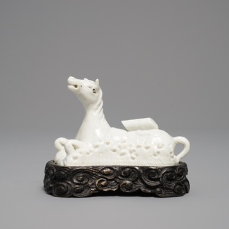 Un modèle d'un cheval en porcelaine blanc de Chine de Dehua sur socle sculpté, Kangxi