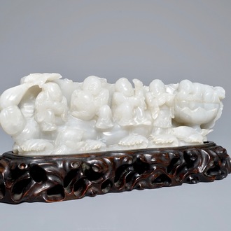 A Chinese white jade group with boys on a raft on carved wooden base, Qing