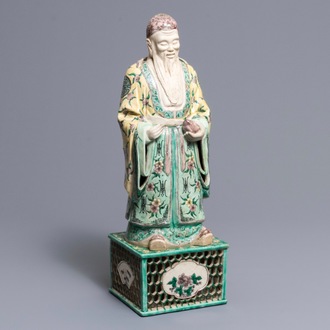 A large Chinese verte biscuit figure of an immortal on reticulated stand, Kangxi