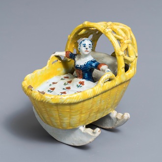 A polychrome Dutch Delft model of a girl in a cradle, 18th C.
