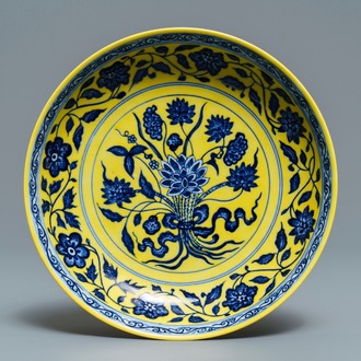 Une assiette en porcelaine de Chine à décor d'un bouquet en bleu et blanc sur fond jaune, marque de Qianlong, 19/20ème