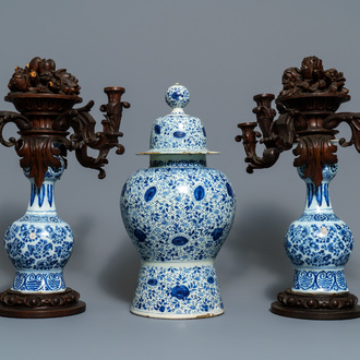 A Dutch Delft blue and white three-piece garniture with carved wooden candleholders, 18th C.