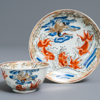A Chinese iron red, grisaille, gilt and overglaze blue 'carps and crane' cup and saucer, Yongzheng