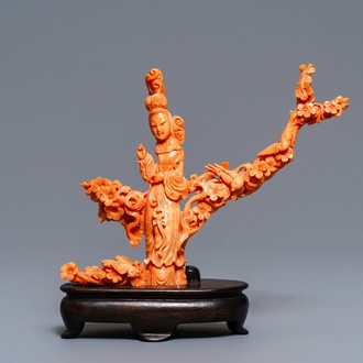 A Chinese carved red coral group of a lady among blossoming branches, 19th C.