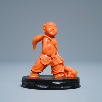 A Chinese carved red coral group of a boy with a dog, 20th C.