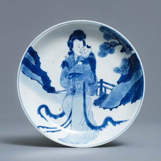 Een Chinees blauw-wit semi-eierschaal bord met een dame die een kind draagt, Kangxi