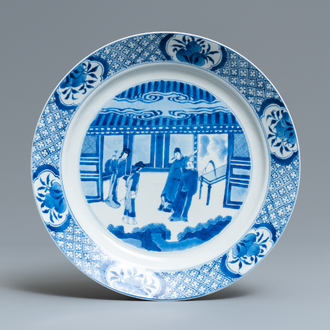 Un plat en porcelaine de Chine en bleu et blanc à décor de figures dans un intérieur, marque et époque de Kangxi