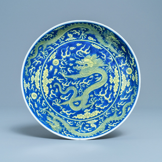 Un plat en porcelaine de Chine en bleu et jaune à décor d'un dragon, marque et époque de Qianlong
