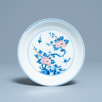 A Chinese blue, white and copper red saucer dish with floral design, Kangxi