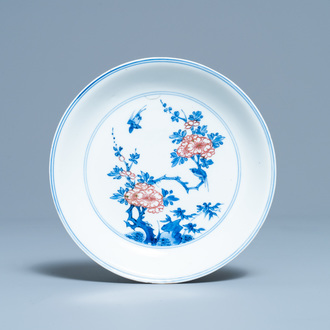 A Chinese blue, white and copper red saucer dish with floral design, Kangxi
