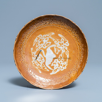 Une assiette en porcelaine de Chine à décor d'une grue sur fond brun, fours de Swatow, Ming