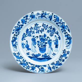 Un plat en porcelaine de Chine en bleu et blanc à décor de femmes autour d'une jardinière, Kangxi
