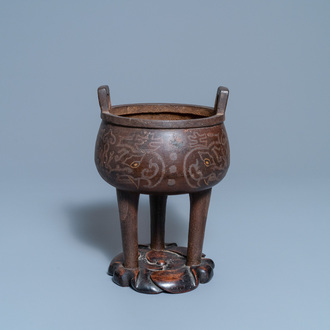 Een Chinese ingelegde bronzen driepotige wierookbrander op houten sokkel, Ming