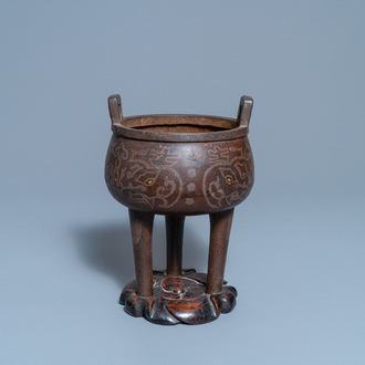 A Chinese inlaid bronze tripod censer on wooden stand, Ming