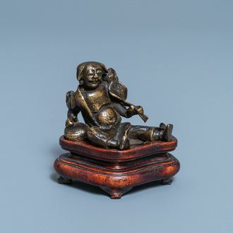 A Chinese bronze 'Liu Hai' scroll weight on wooden stand, Ming