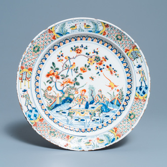 Een polychrome Engelse Delftware schotel met een chinoiserie theescène, 18e eeuw