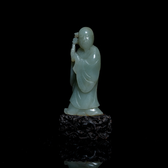 A Chinese carved celadon jade 'immortal' figure on wooden stand, Qing