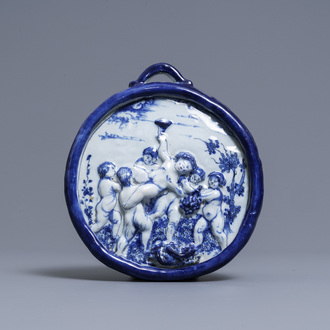 A Dutch Delft blue and white relief-moulded plaque with putti holding grapes, 18th C.