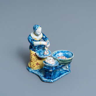 A rare polychrome Dutch Delft figure of a butcher's lady stuffing sausages, 18th C.